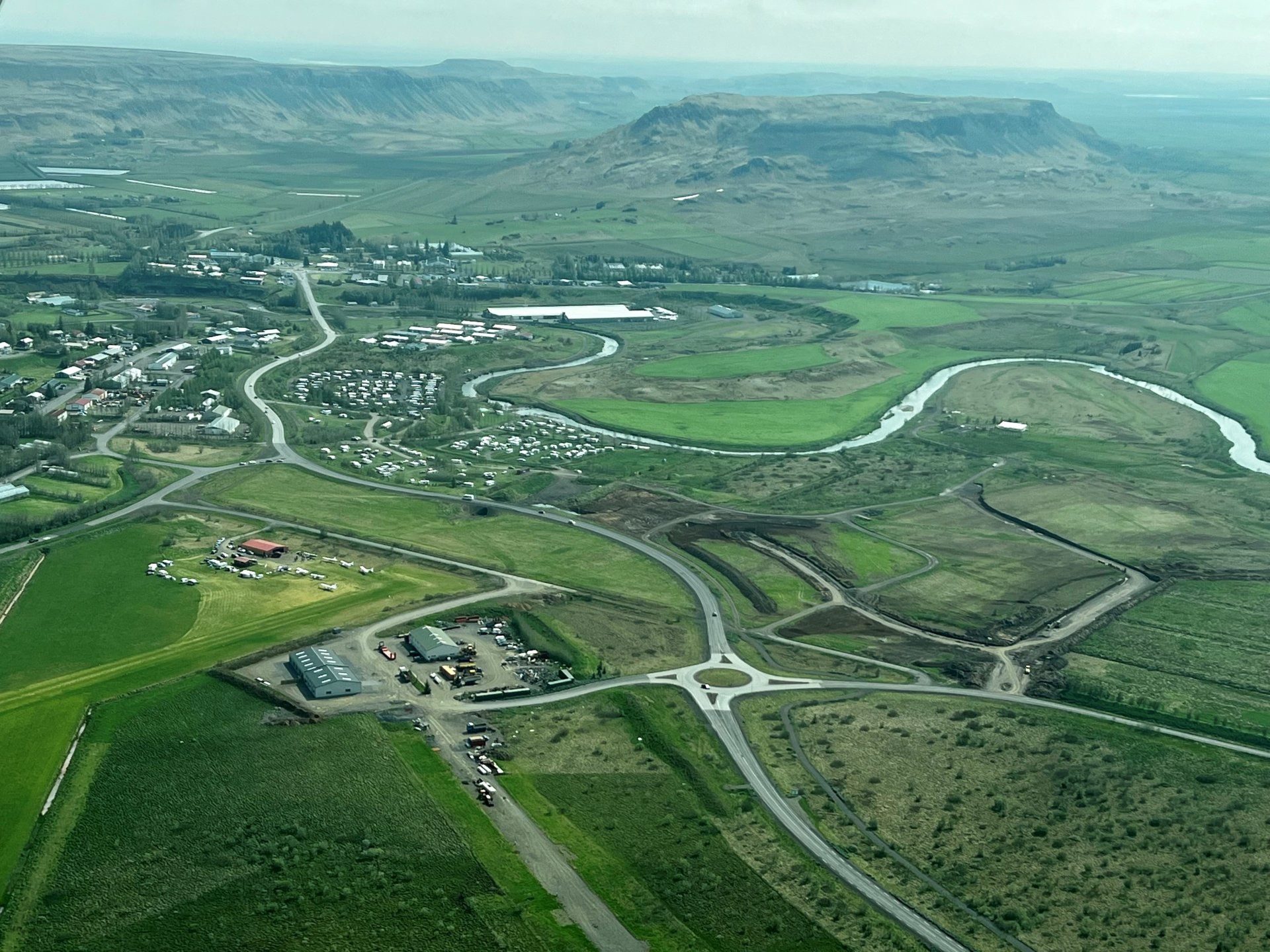 Fremst á myndinni má sjá Iðjuslóðina.  Nýja íbúðahverfið kennt við Kerlingargjöll er fjær og þar er uppbygging nú í fullum gangi.   Flugvöllurinn á Flúðum er síðan austan við Iðjuslóð.
Myndin er tekin sumarið 2023